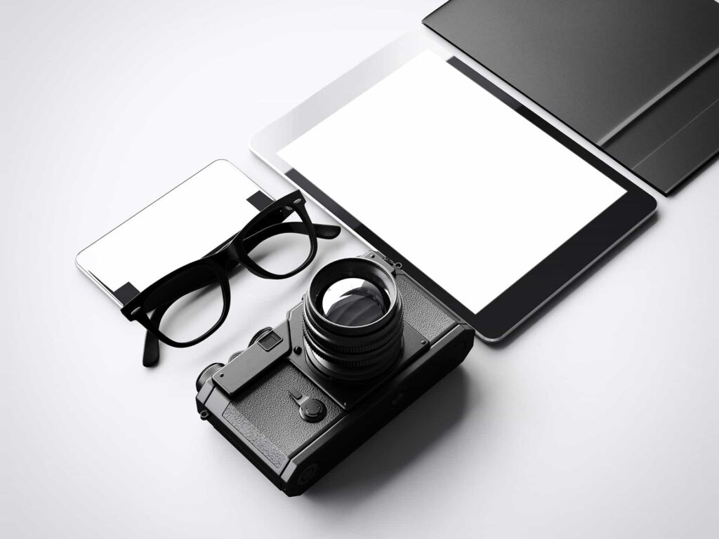 Junto a una cámara de fotos antigua, vemos un móvil, una tableta, unas gafas y una subcarpeta