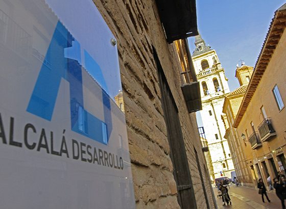 En la fachada de un edificio antiguo en una calle peatonal vemos un cartel de Alcalá Desarrollo