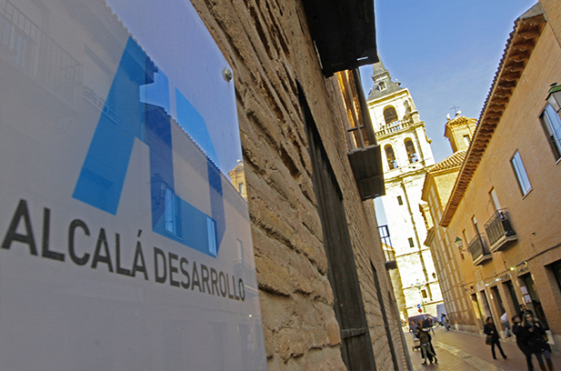 En la fachada de un edificio antiguo en una calle peatonal vemos un cartel de Alcalá Desarrollo