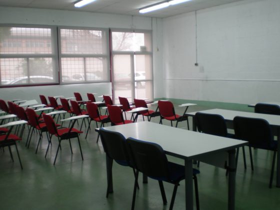 Vista interior de un aula dónde vemos sillas individuales con pupitre incorporadao y mesas dobles