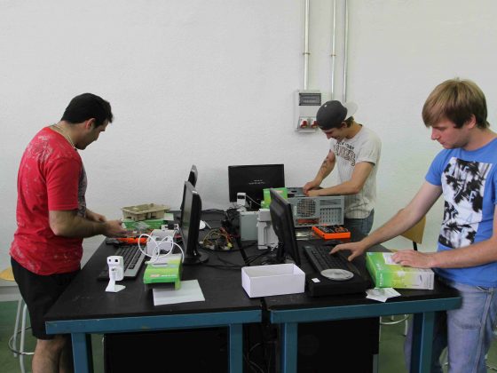 Varias personas aprendiendo a montar, reparar y configurar ordenadores en dos mesas de trabajo